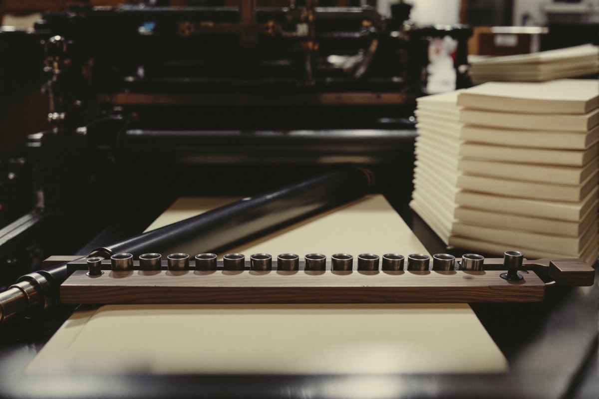 Prensa tipográfica antigua con tipos móviles y papel sin cortar